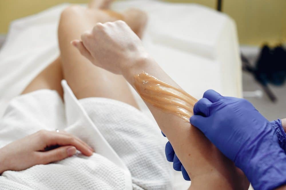 Technician applying sugaring paste for hair removal.