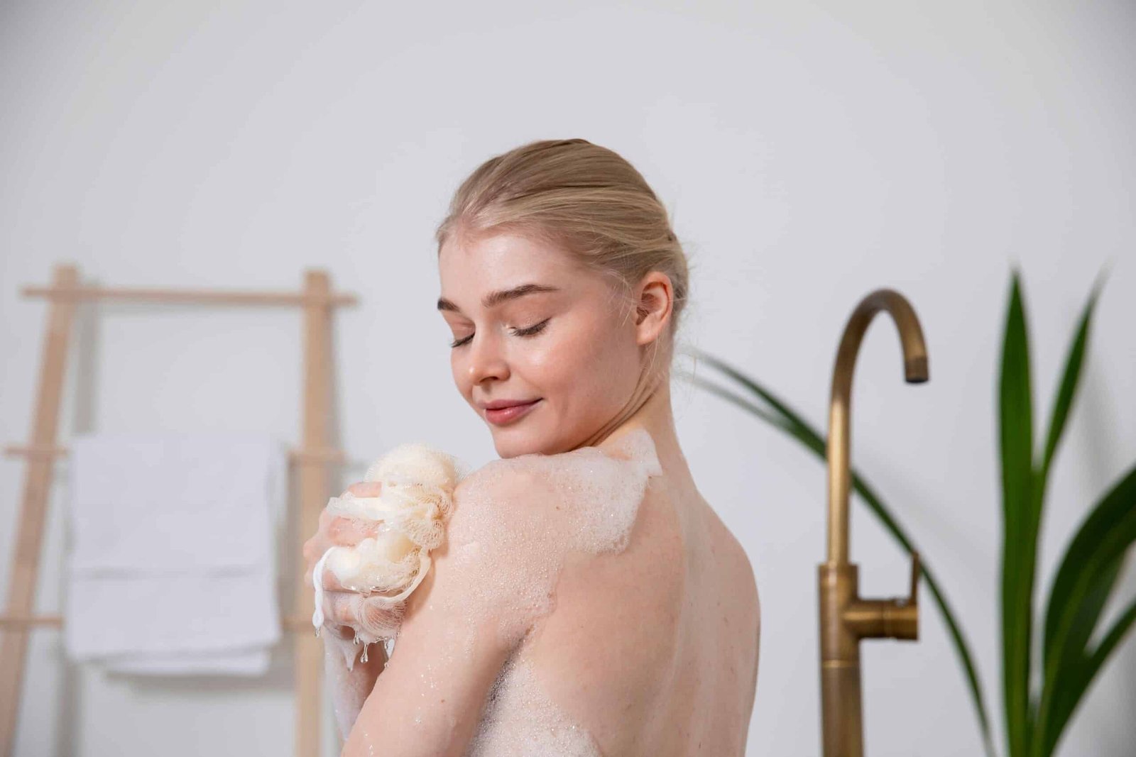 Woman exfoliating skin with a loofah to prepare for a smooth sugaring session.