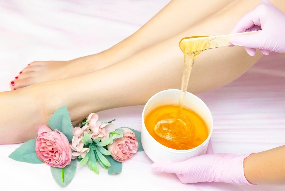 Give An Image Of A Bowl Of Sugar Wax With A Wooden Spatula, Showcasing The Simple Ingredients Used For Hair Removal.