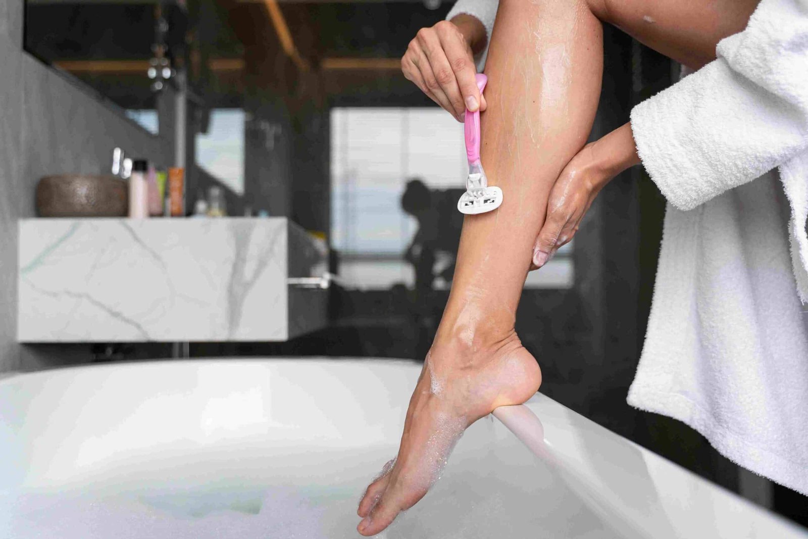 Image Showing A Women Shaving Their Leg And Arm With A Razor.